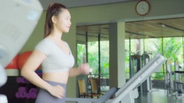 Spor salonundaki koşu bandında koşan çekici Asyalı kadın sporcu.