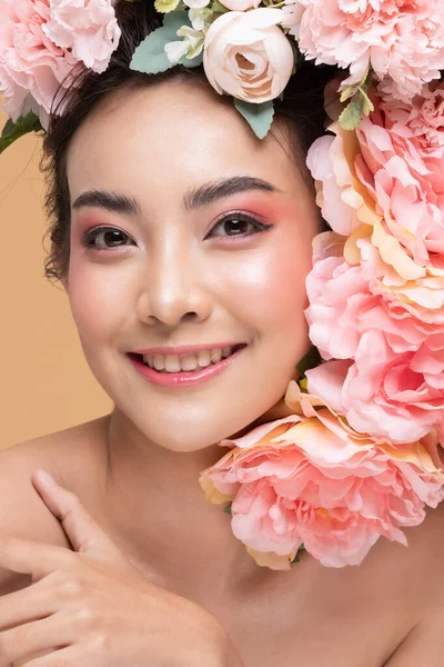 Beauty Asian young woman with big bouquet flowers on head smile with clean fresh skin Happiness and cheerful with positive emotional on Beige background,Beauty Cosmetics and Facial treatment Concept