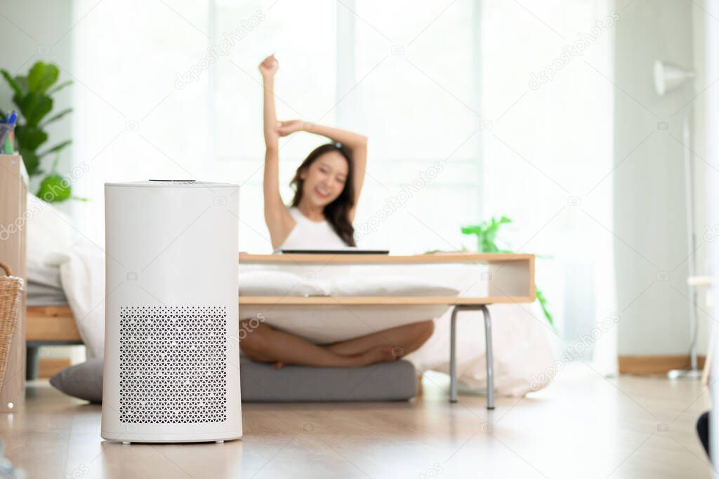 air purifier in living room for clean and fresh air with woman stretching hands and relax in background