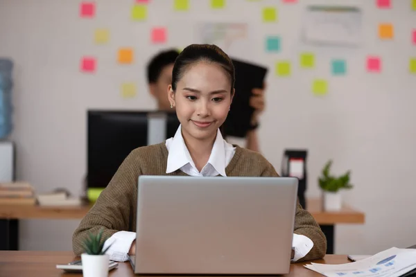 Happy Asian business woman in casual working with laptop and smile looking at camera at modern office or Co-Working Space,Business Startup Concept