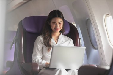 Asyalı genç bir kadın uçuşta, seyahatte ve iş hayatında birinci sınıfta pencerelerin yanında oturuyordu.