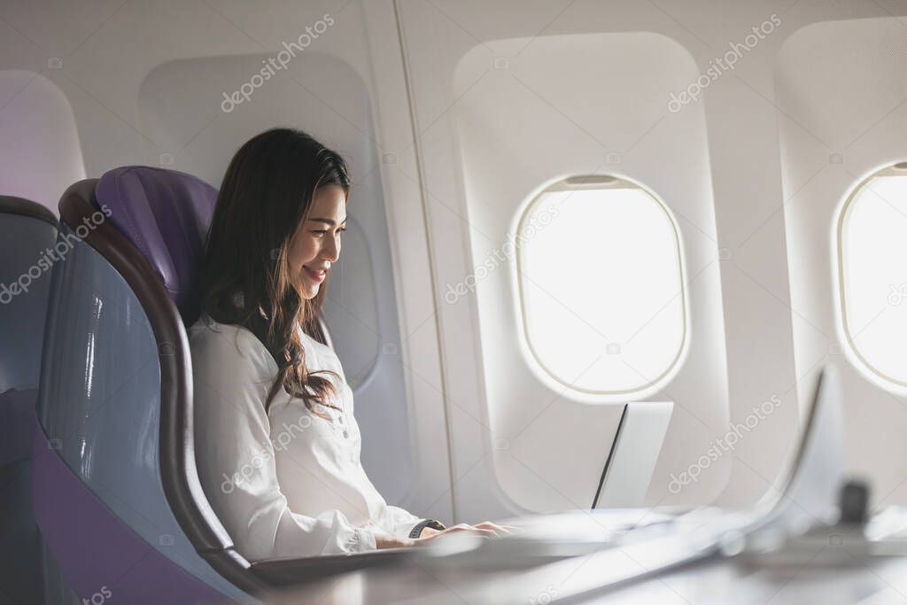 Asian young woman using laptop sitting near windows at first class on airplane during flight,Traveling and Business concept