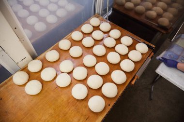 Mutfak masasında taze çiğ hamur topları var. Fırın, ekmek, fırın ürünleri, ekmek ve hamur üretimi ve satışı kavramı