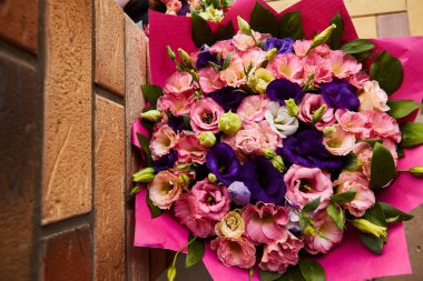 Renkli bir buket yaz çiçeği. Tuğladan bir zemin üzerinde pembe ve mor çiçeklerin bileşimi.