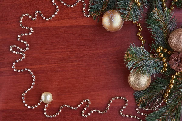 Çerçeve, ahşap bir masanın üzerinde altın süsler taşıyan yeşil dalları olan kozalaklı ağaçlardan yapılmıştır. Yeni yıl kavramı, parlak bir aile bayramı kutlaması.