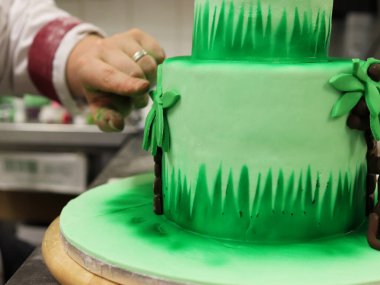 Aşçı pastaya badem ezmesi yaprağı yapıştırıyor..