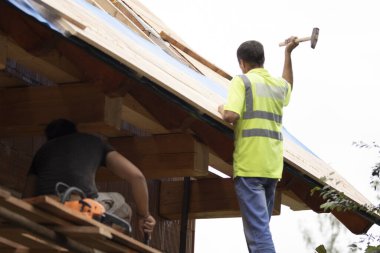 İşçi, çatının yeniden inşası sırasında bataryaya çivi çakıyor..