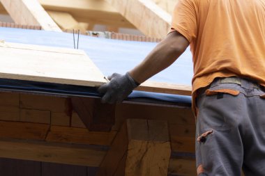 İşçi, çatıya çivi çakmak için bir tabur hazırlıyor..