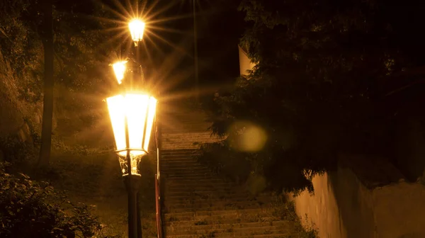 Uzun merdivenler boyunca duran eski lambaların gece fotoğrafı.