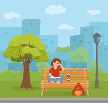 Kitap okuyan genç bir kadın parkta bir bankta oturuyor..