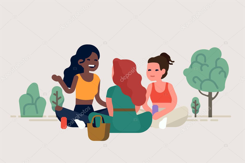 Three girl friends having a picnic in a park sitting around talking to each other