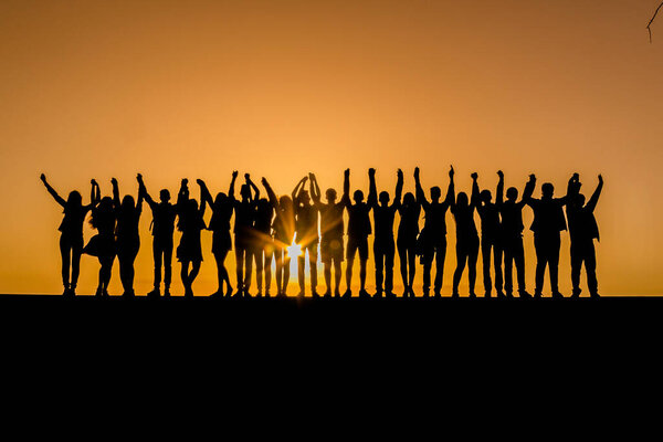 Silhouettes of children against the sunset with their hands up. Goodbye school. Prom. Banner. A place for text. Photo in the background of the sun. Friendship