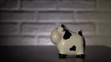 4 bin. Erkek eli yakın, bozuk para atıyor, kumbaraya avro atıyor. Siyah benekli beyaz para depolamak için gülümseyen inek.