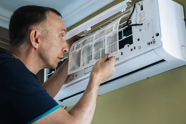 A man cleans the filter of a household air conditioner. Cleaning of premises.