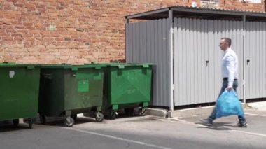 4 bin. Gözlüklü bir Avrupalı, yeşil çöp tenekesine yiyecek atıkları atıyor..