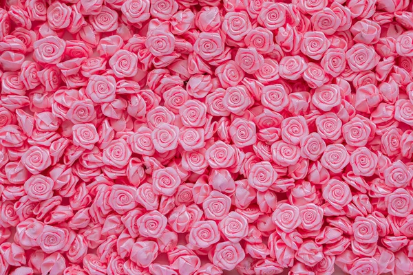 Saten kurdelelerden yapılmış pembe çiçekler, dikiş aksesuarları, giysi için mücevherler. Mesaj için yer.