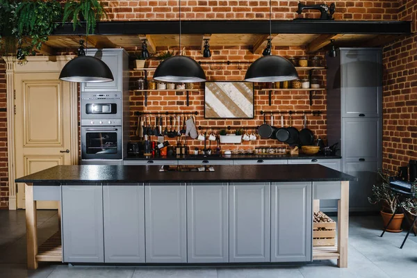 Kitchen interior with brick wall and grey furniture with kitchenware