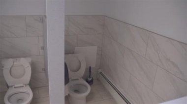 Tuvalet odasının minimalist iç dekorasyonu fayanslı duvar ve zemin klasik beyaz seramik klozet, el havuzu, tuvalet kağıdı tutacağı ve çöp tenekesi..