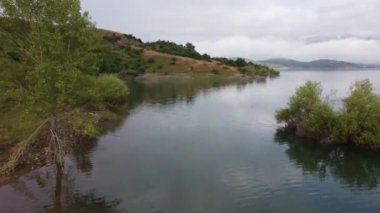 İspanya 'nın kuzeyindeki dağın zirvesinde ve adadaki gölün üzerindeki sabah sisinin hava aracı görüntüsü.