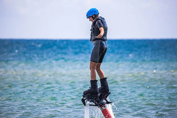 Er vliegt een jonge vrouw aan het vliegenbord. Waterextreme sport Rechtenvrije Stockfoto's