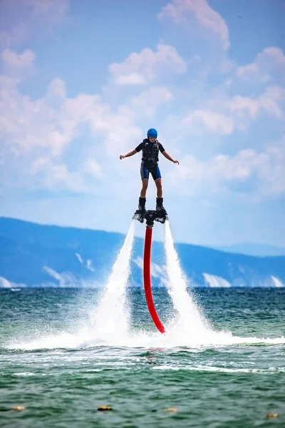 La giovane donna sta volando verso il flyboard acquatico. Sport estremi acquatici — Foto Stock