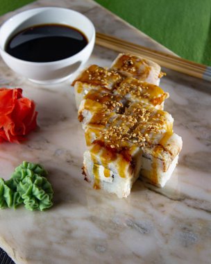 Suşi. Soya sosu, wasabi ve zencefil turşulu mermer bir tahtanın üzerinde taze Japon dürümleri..