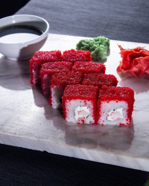 Suşi. Soya sosu, wasabi ve zencefil turşulu mermer bir tahtanın üzerinde taze Japon dürümleri..