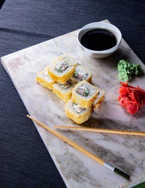 Suşi. Soya sosu, wasabi ve zencefil turşulu mermer bir tahtanın üzerinde taze Japon dürümleri..