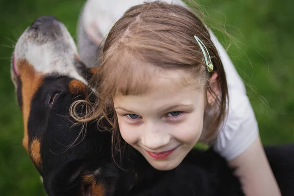 Çocuk ve köpek. Kız köpeğe sarılıyor.