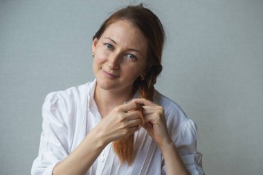 Bir kızın portresi, uzun kızıl saçlarını ören bir kadın.