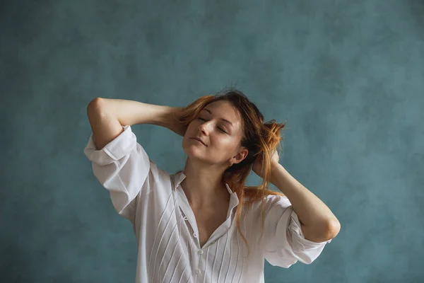 Bir kız, kızıl uzun saçlarını elleriyle tutan bir kadın.