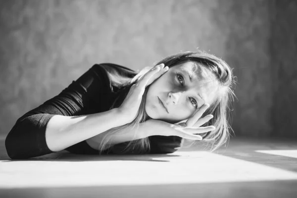 Genç bir kız yerde yatar ve izleyiciye bakar.