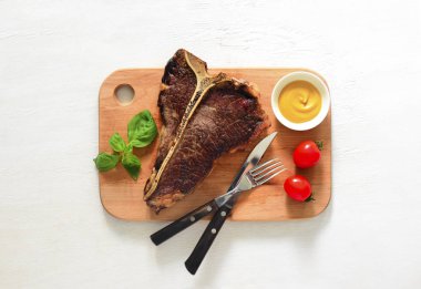 T-Bone biftek hissesini bir kesme tahtası üzerinde hizmet, yukarıdan görüntülemek