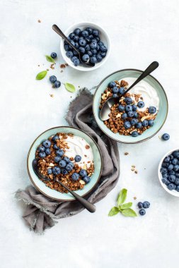 Granola ve yaban mersinli kahvaltı. Sade yoğurt. Masanın genel görünüşü, sağlıklı gıda kavramı.
