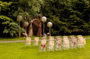 Balonlu düğün yeri ve büyük bir ağacın yanında duran sandalyeler.