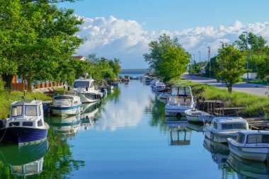 Her iki tarafında renkli tekneler ve ağaçlarla çevrili nehir kenarındaki şaşırtıcı kanal.