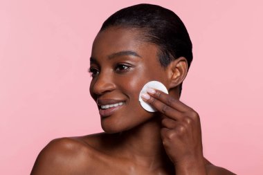 Young woman using cotton pad, studio shot 