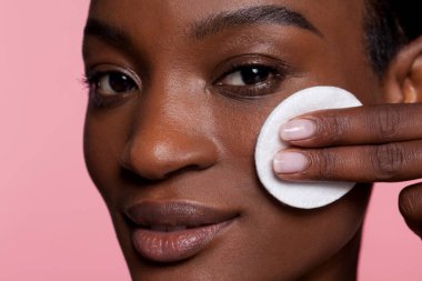 Young woman using cotton pad, studio shot 