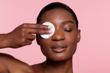Young woman using cotton pad, studio shot 