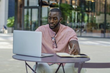 Man working with laptop at table in sidewalk cafe