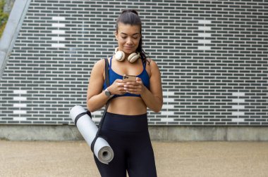 Yoga minderli kadın akıllı telefon kullanıyor.