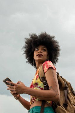 Sırt çantalı genç bir kadın telefon kullanıyor.