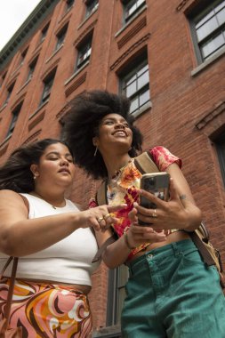 Tuğla binanın önünde iki kadın, düşük açılı.