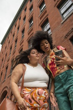 Tuğla binanın önünde iki kadın, düşük açılı.