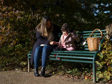 Mother and daughter with Down syndrome sitting on bench