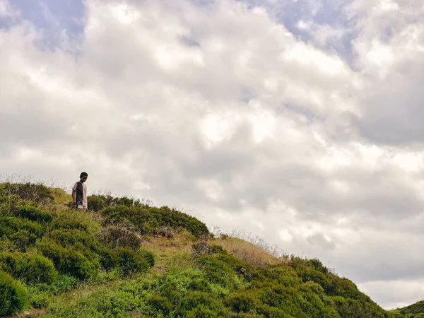 Vahşi doğada çim tepelerinde yürüyen bir çocuk