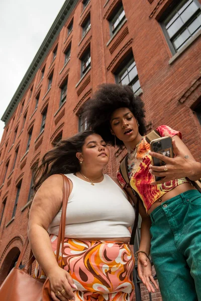 Tuğla binanın önünde iki kadın, düşük açılı.