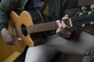 Young man playing acoustic guitar, close up
