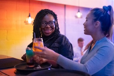 Female friends drinking cocktails at bar counter