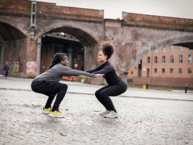 Athletic man and woman doing squats outdoors